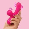 A hand holding a vibrant pink vibrator against a soft pink background.