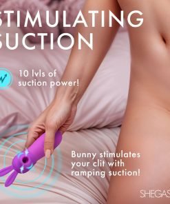 Close-up of a hand holding a purple suction toy on a bed