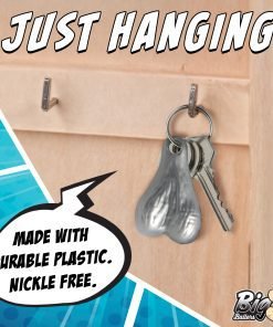 A quirky key holder shaped like a pair of testicles, hanging on a wooden backdrop.