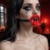 Woman with dramatic makeup and a red mouth gag in a dimly lit room