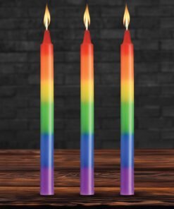Three colorful rainbow candles with flames on a wooden table
