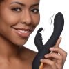 A woman smiling while holding a sleek black personal massager
