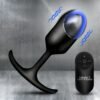 A sleek black vibrating plug with a remote control on a metallic background.