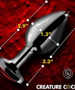 Glossy black anal plug on a textured red background with measurement indicators