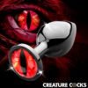 A decorative butt plug with a striking red gemstone resembling a reptilian eye, set against a fiery background.