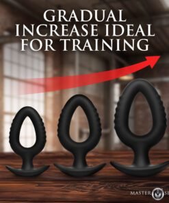 Three black training plugs of varying sizes displayed on a wooden surface with a ruler